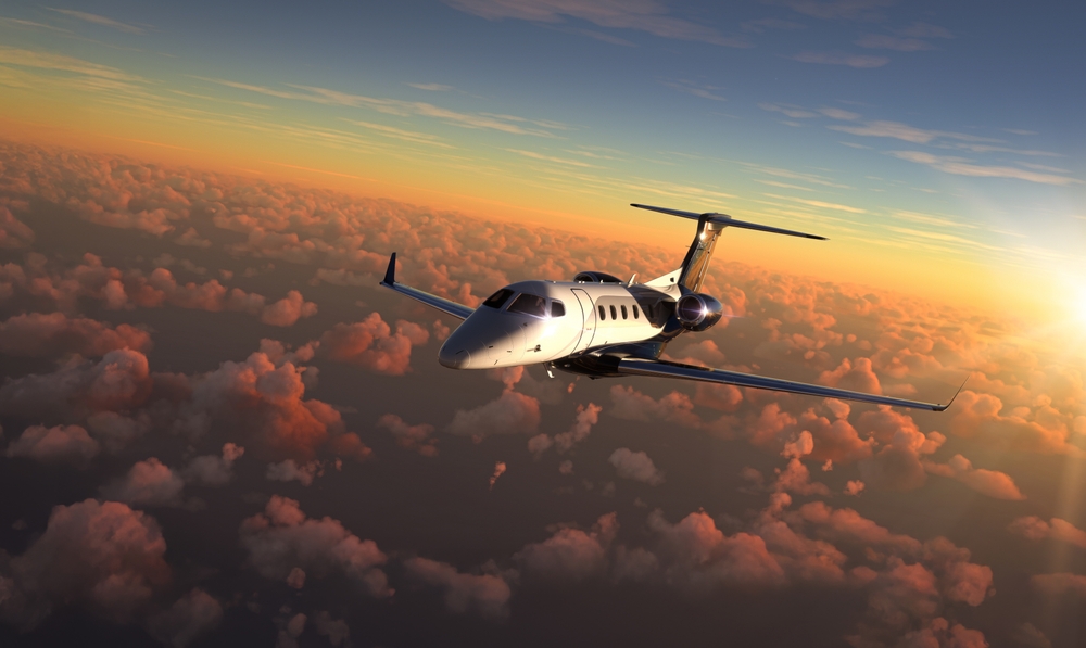 Private jet flying over sunset
